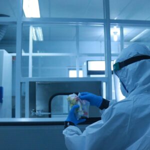 Company Lab technician in full protective suit performs tasks in a controlled laboratory environment.